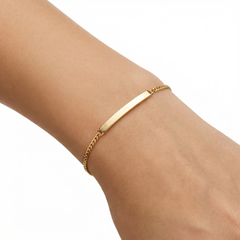 Gold bracelet on a person's wrist against a white background