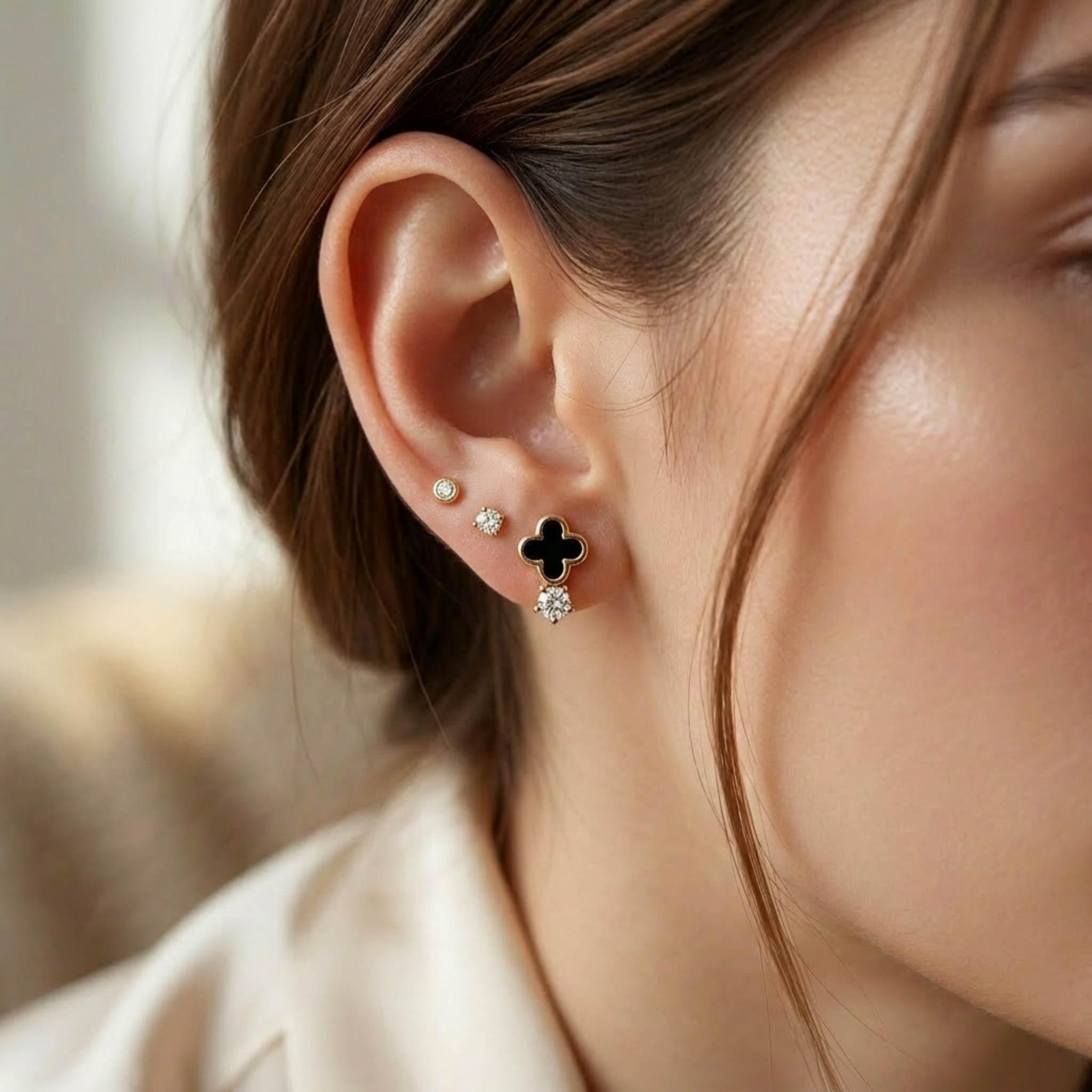 Small 14k yellow gold clover studs for curated ear mapping on white background