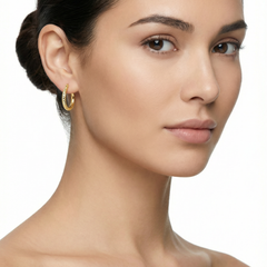 Close-up of a woman wearing gold hoop earrings on a white background