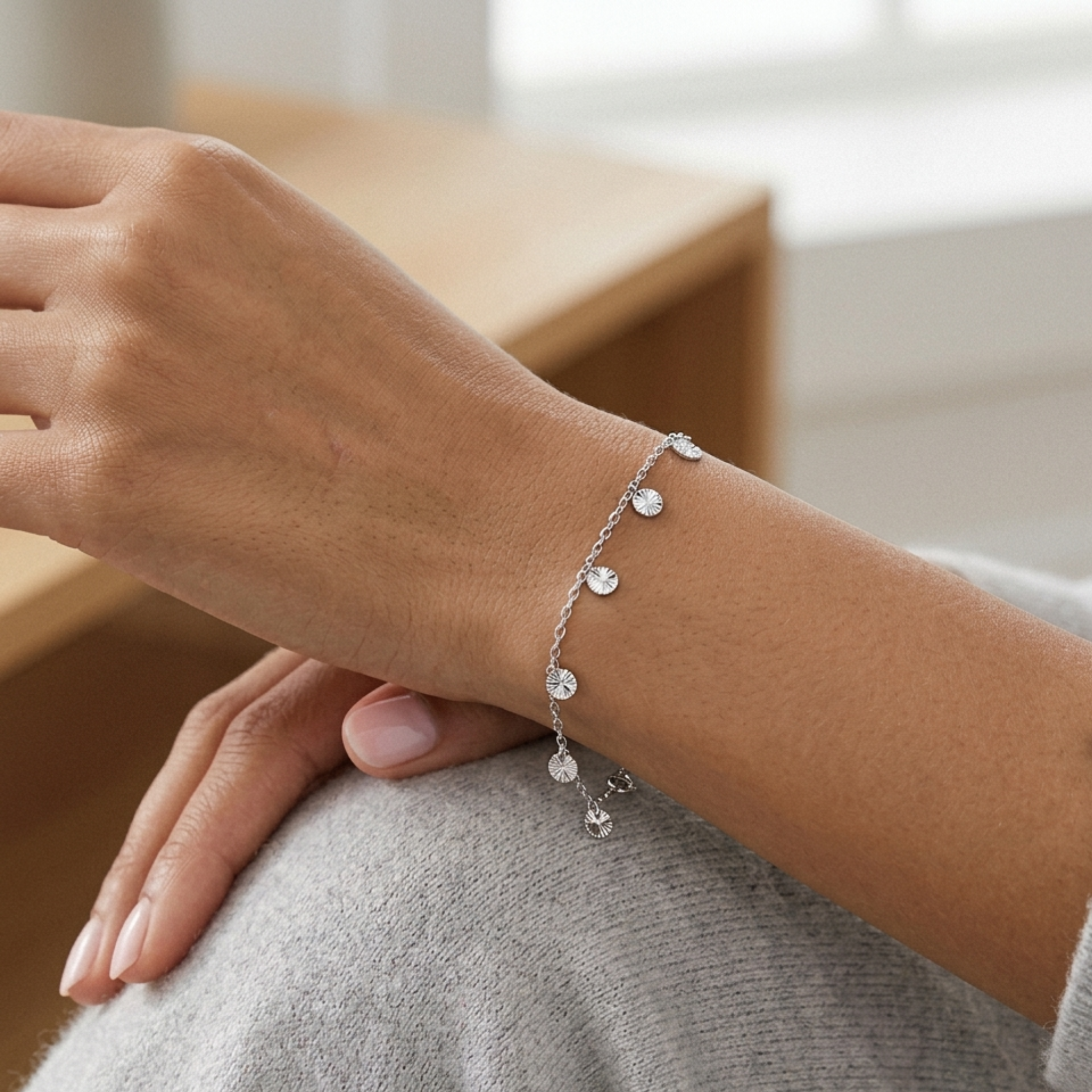 14k white gold bracelet with small round embellishments on a wrist, blurred background