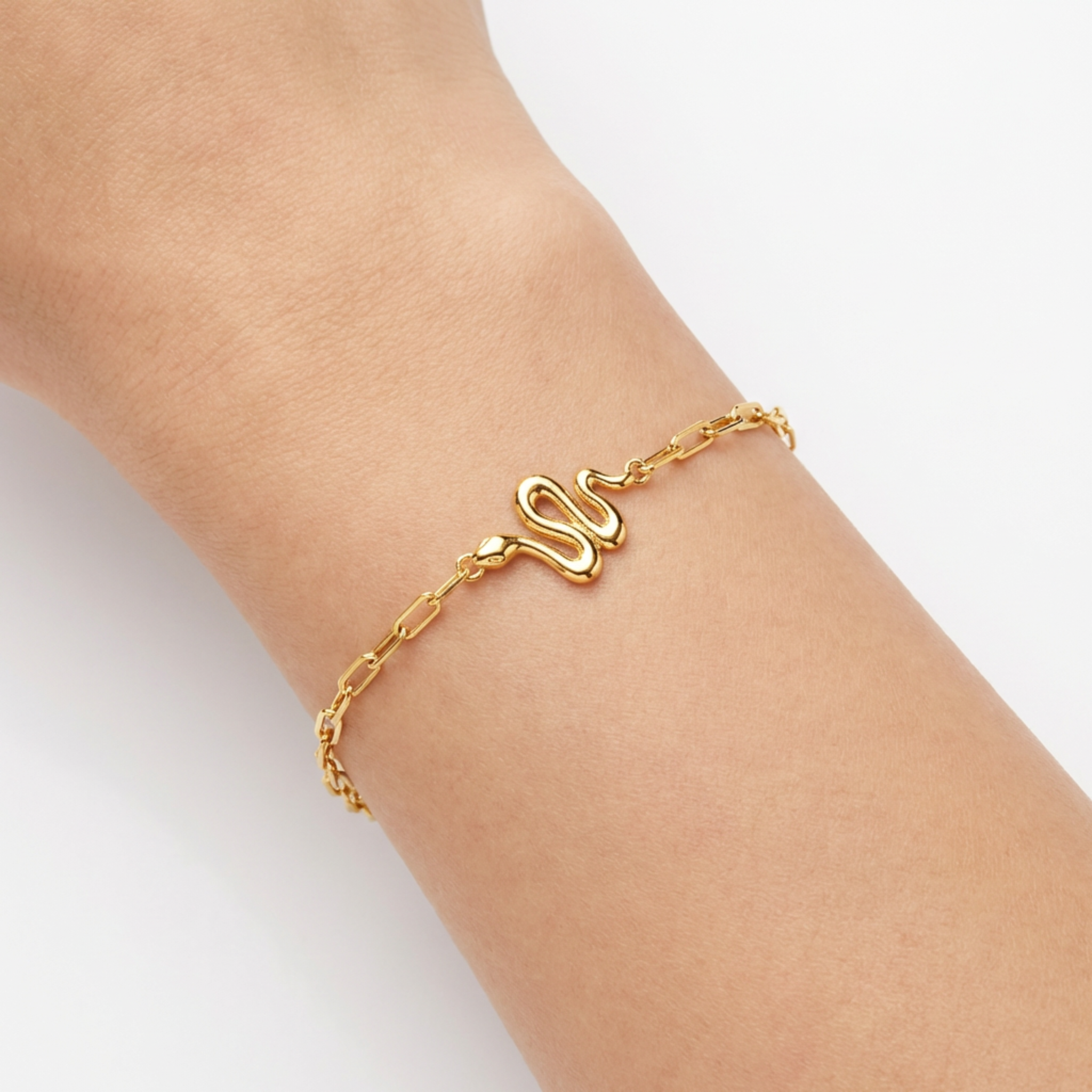 Minimal gold snake bracelet close-up with polished charm detail