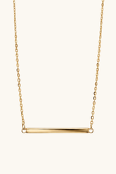 Gold necklace with a bar pendant on a white background