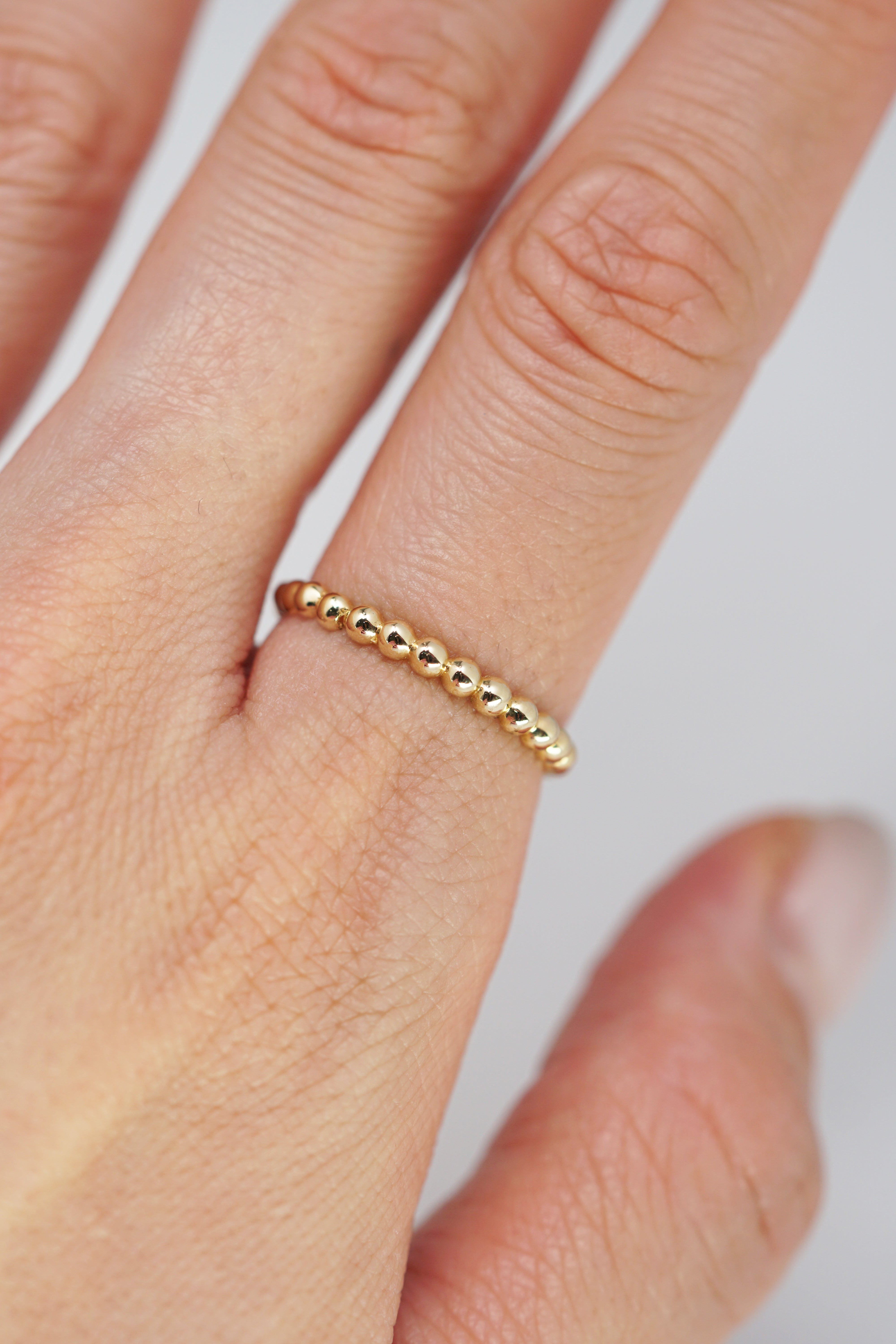 14k solid gold yellow beads on index finger model shot