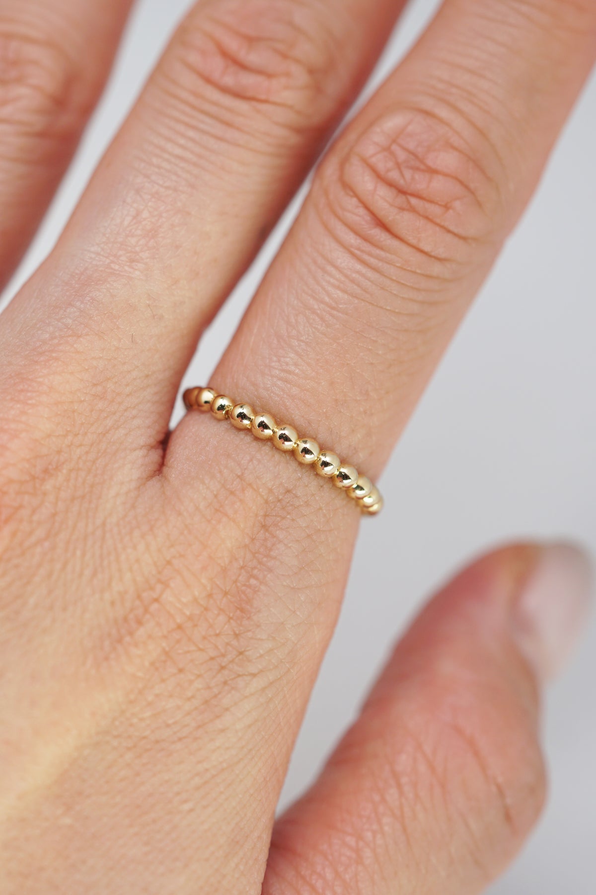 14k solid gold yellow beads on index finger model shot