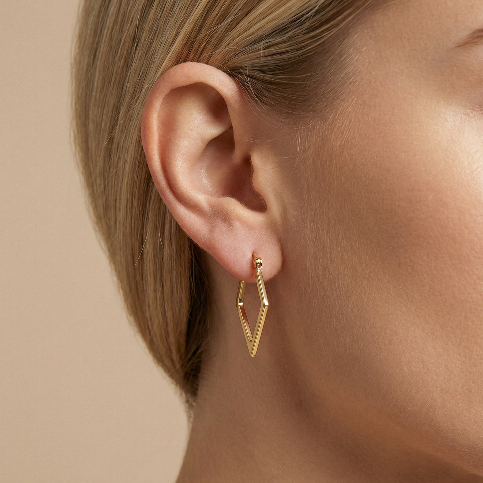 High polish 14k gold elongated diamond hoops on white background